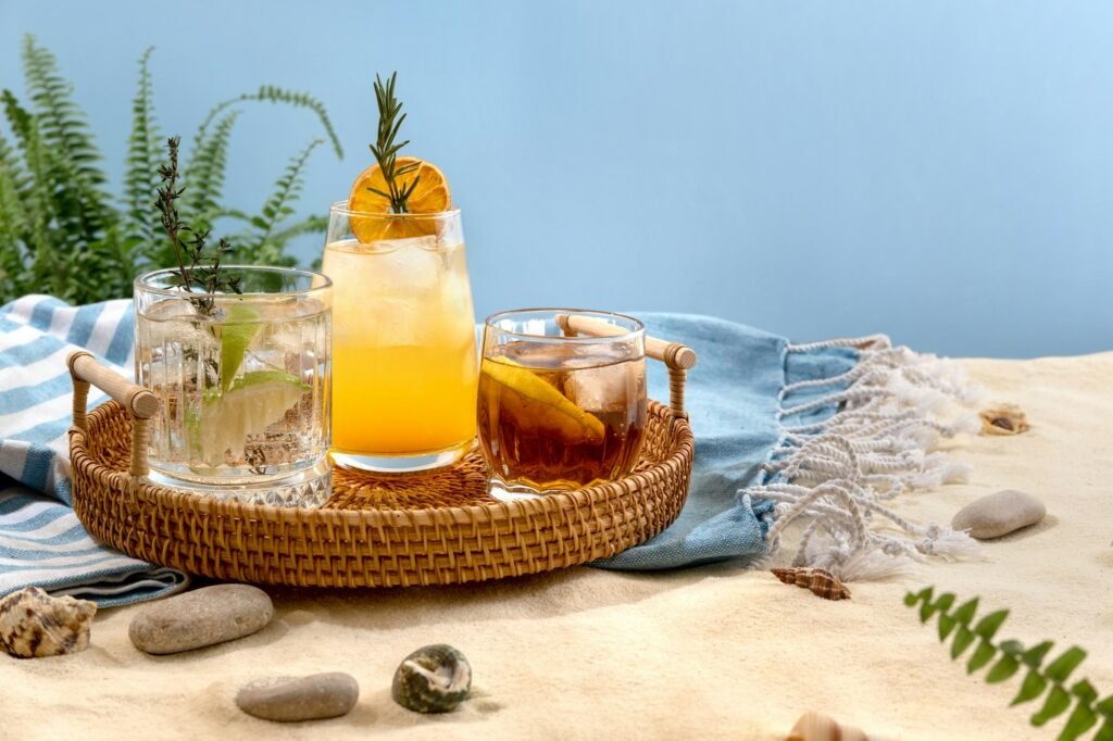 Exotic summer drinks on a wicker tray on beach with white sand.